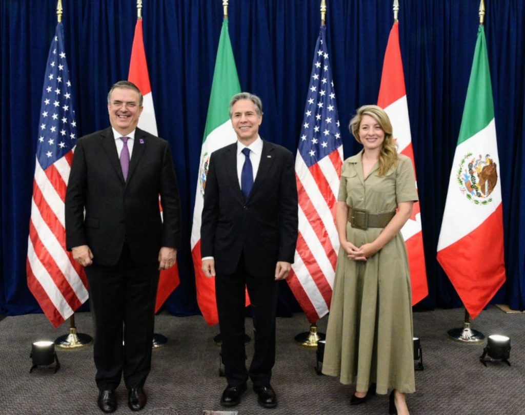 Photo of Marcelo Ebrard, Anthony Blinken and Minister Joly, smiling and posing in front of the flags of the United States, Canada and Mexico. 